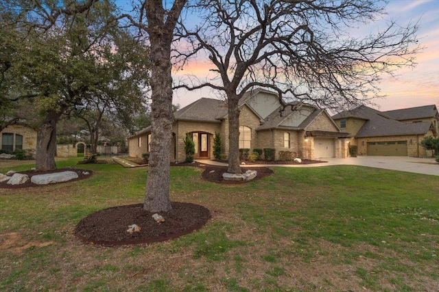 french provincial home featuring a garage, a yard, brick siding, and driveway