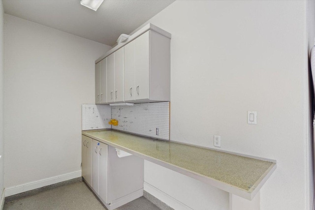 kitchen featuring tasteful backsplash, light countertops, baseboards, and white cabinetry