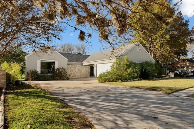 ranch-style home featuring driveway, a front lawn, an attached garage, and stucco siding