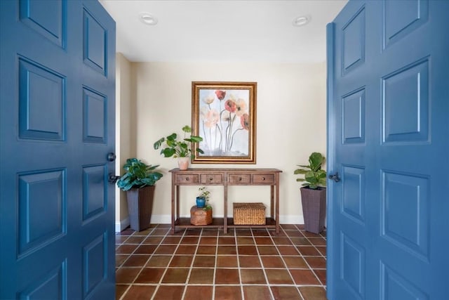 entrance foyer with dark tile patterned floors and baseboards