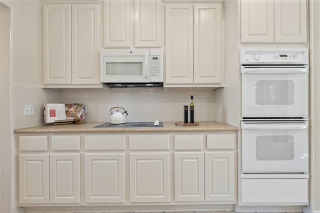 kitchen with white appliances, light countertops, decorative backsplash, and white cabinets