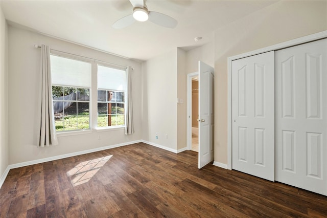 unfurnished bedroom with a closet, dark wood finished floors, baseboards, and ceiling fan