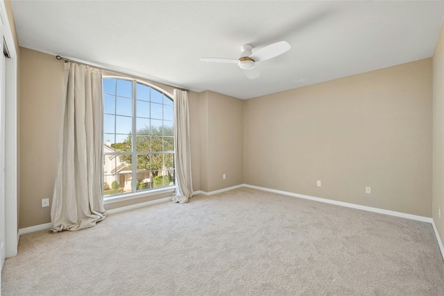 carpeted empty room featuring ceiling fan and baseboards