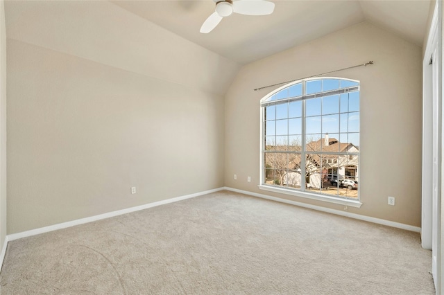 empty room featuring carpet floors, baseboards, and lofted ceiling