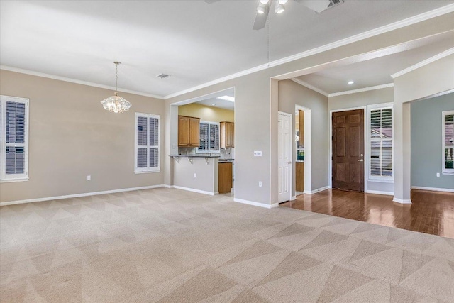 unfurnished living room with visible vents, baseboards, light colored carpet, ornamental molding, and ceiling fan with notable chandelier