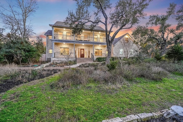 back of property featuring covered porch and a balcony