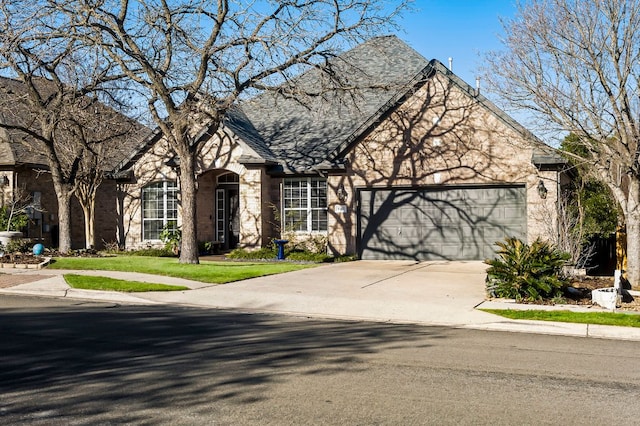 view of front of home featuring a garage, concrete driveway, roof with shingles, and stone siding