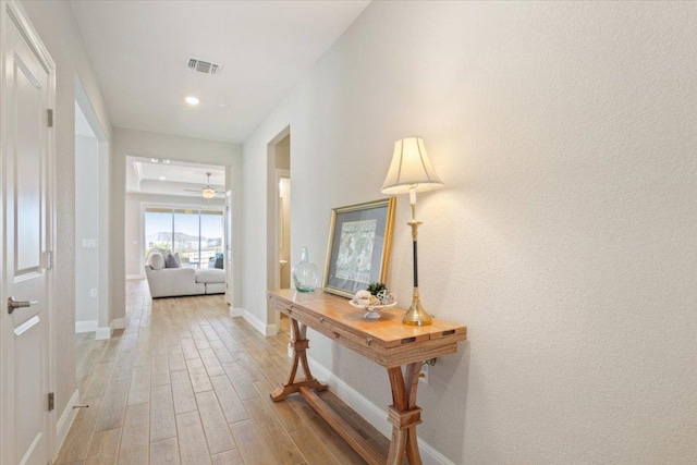 hall with light wood-style floors, recessed lighting, visible vents, and baseboards