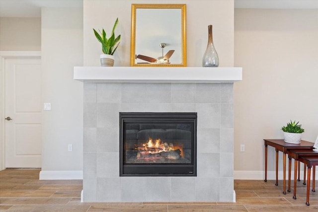 room details featuring baseboards, a tiled fireplace, and wood tiled floor