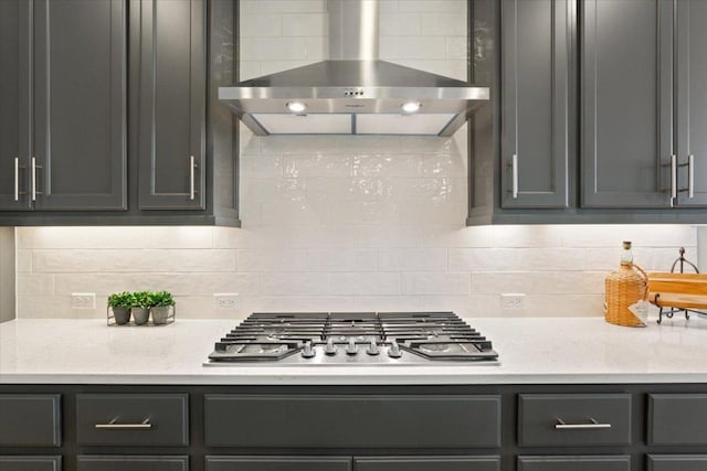 kitchen with stainless steel gas cooktop, wall chimney exhaust hood, light stone countertops, and decorative backsplash