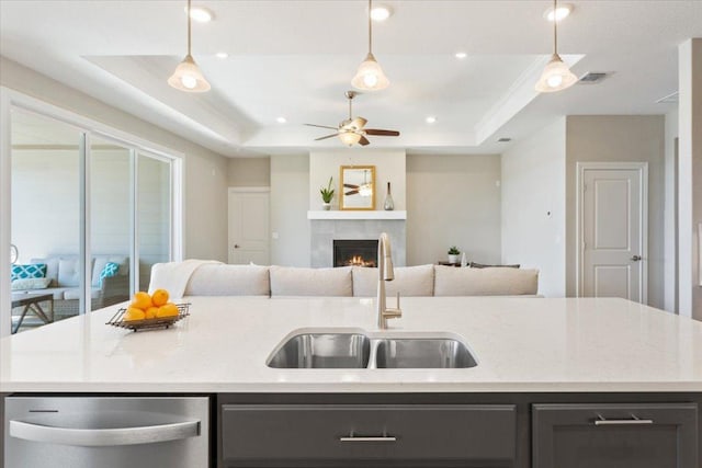 kitchen with a sink, stainless steel dishwasher, open floor plan, and a raised ceiling