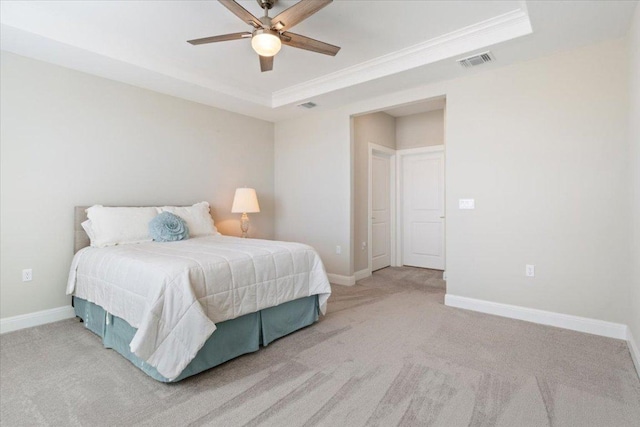 bedroom with light carpet, a tray ceiling, visible vents, and baseboards