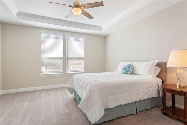 bedroom with baseboards, a tray ceiling, carpet flooring, and crown molding