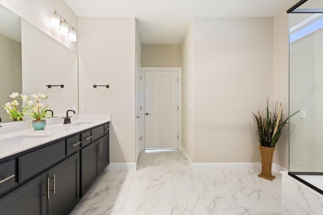 full bath with marble finish floor, a sink, baseboards, and double vanity