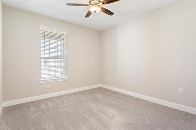 carpeted spare room featuring a ceiling fan and baseboards