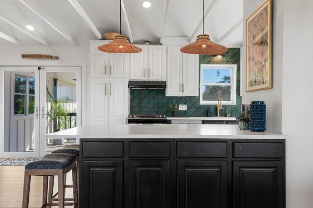 200 Hilltop Dr, Dripping Springs, TX 78620 - kitchen featuring dark cabinetry, a breakfast bar, light countertops, under cabinet range hood, and beam ceiling