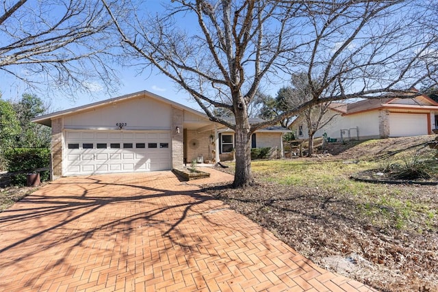 single story home featuring decorative driveway, brick siding, and an attached garage