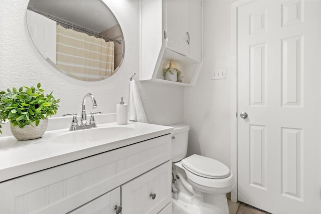 full bath featuring a textured wall, vanity, toilet, and tile patterned floors