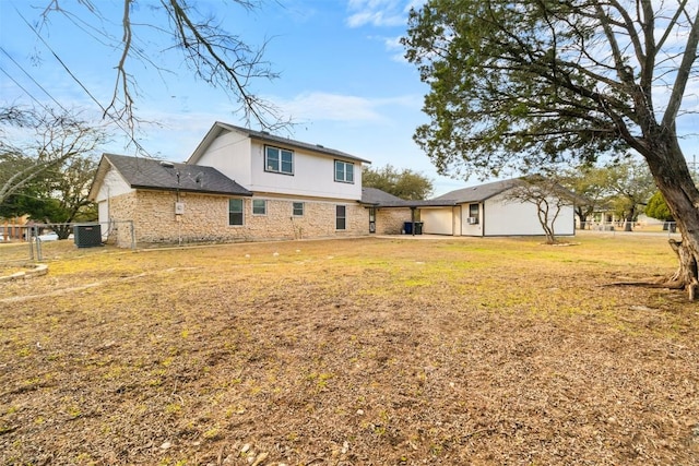 rear view of property with stone siding, fence, and a lawn