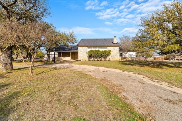 view of home's exterior featuring driveway, a yard, and a chimney