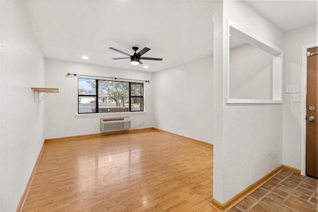 unfurnished living room with a wall unit AC, wood finished floors, and baseboards