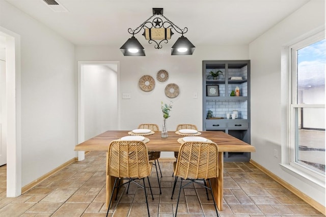 dining space with stone finish flooring, visible vents, and baseboards