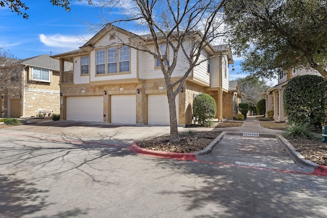 view of front of home featuring driveway, stone siding, and an attached garage