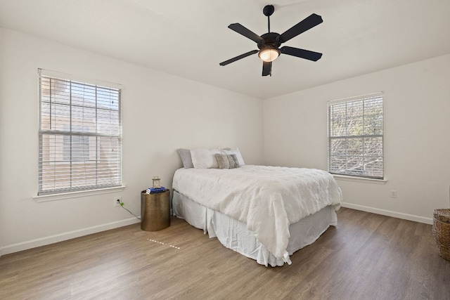 bedroom with ceiling fan, wood finished floors, and baseboards