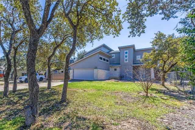 exterior space featuring a garage, driveway, a front lawn, and fence