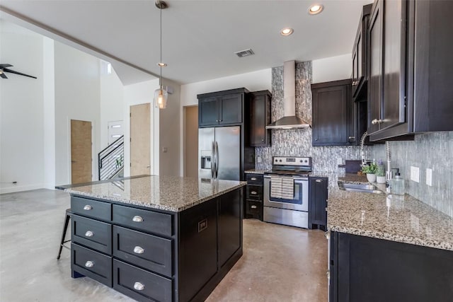 kitchen featuring a center island, stainless steel appliances, visible vents, backsplash, and wall chimney exhaust hood