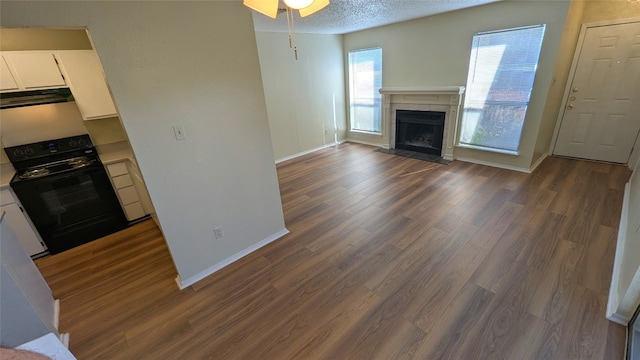 unfurnished living room featuring baseboards, a ceiling fan, dark wood-style floors, a textured ceiling, and a fireplace