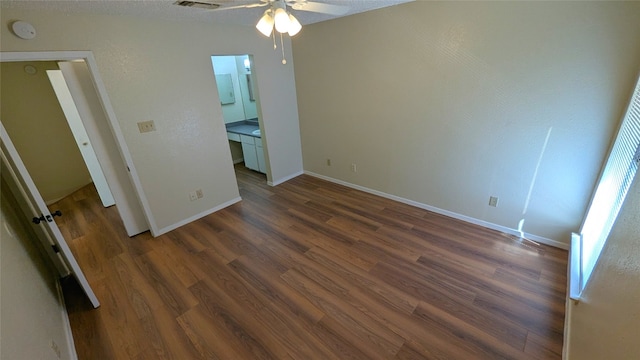 unfurnished bedroom with dark wood-style floors, visible vents, and baseboards