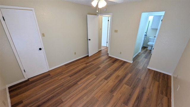 unfurnished bedroom featuring ensuite bathroom, baseboards, and wood finished floors