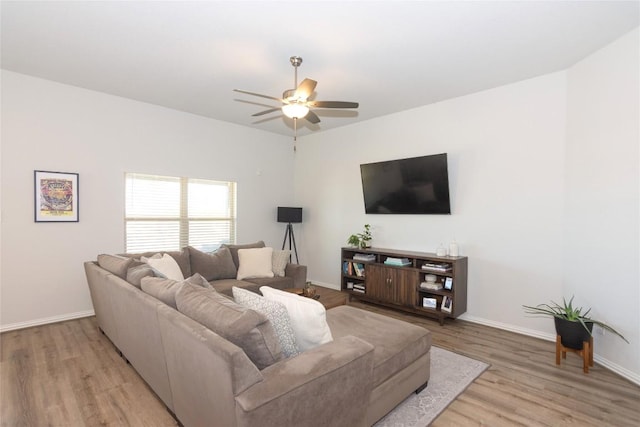 living room with light wood-style floors, ceiling fan, and baseboards