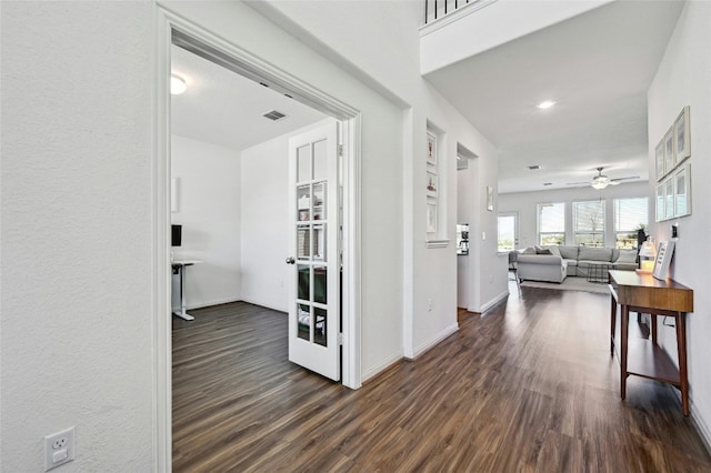 hallway featuring dark wood finished floors, visible vents, and baseboards