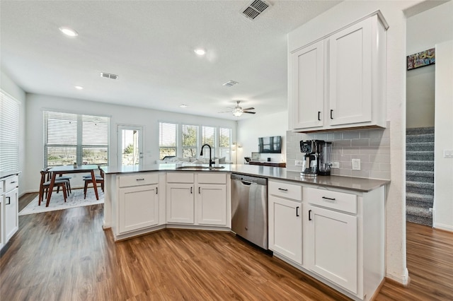 kitchen with visible vents, dark wood-type flooring, a peninsula, stainless steel dishwasher, and a sink