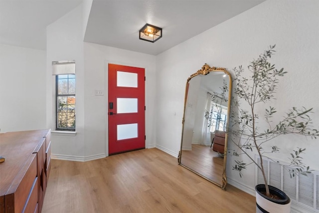 foyer with baseboards, plenty of natural light, and light wood finished floors