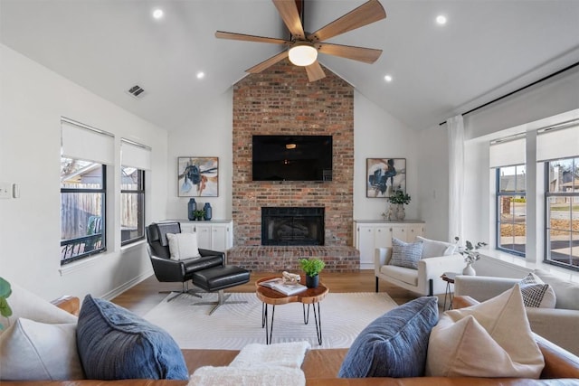 living room with a fireplace, high vaulted ceiling, wood finished floors, and recessed lighting