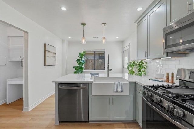 kitchen with stainless steel appliances, tasteful backsplash, gray cabinets, light countertops, and a peninsula