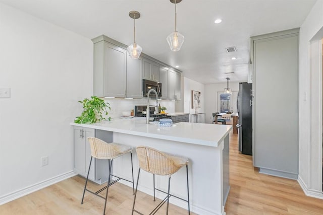 kitchen with stainless steel appliances, light wood-style flooring, gray cabinets, and visible vents