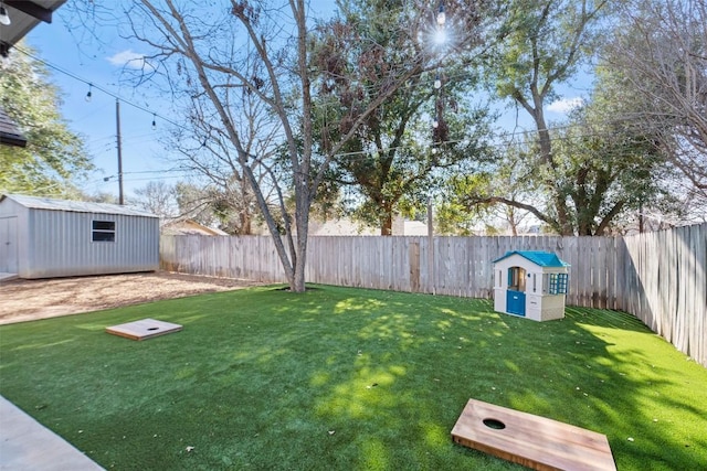 view of yard featuring an outbuilding, a fenced backyard, and a storage unit