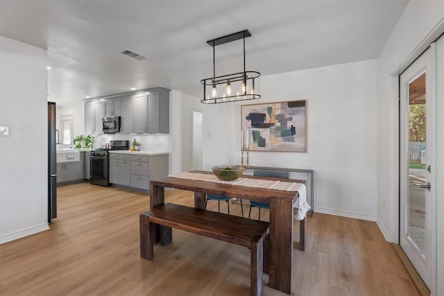 dining room with baseboards, visible vents, and light wood-style floors