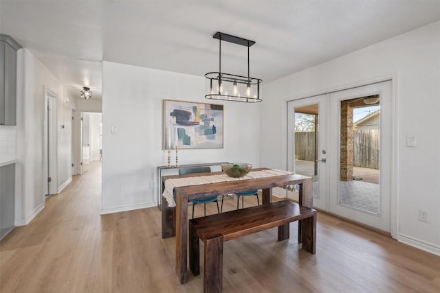 dining area featuring french doors, light wood-style flooring, and baseboards