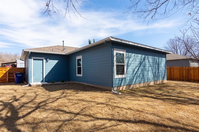 back of property featuring a yard and fence