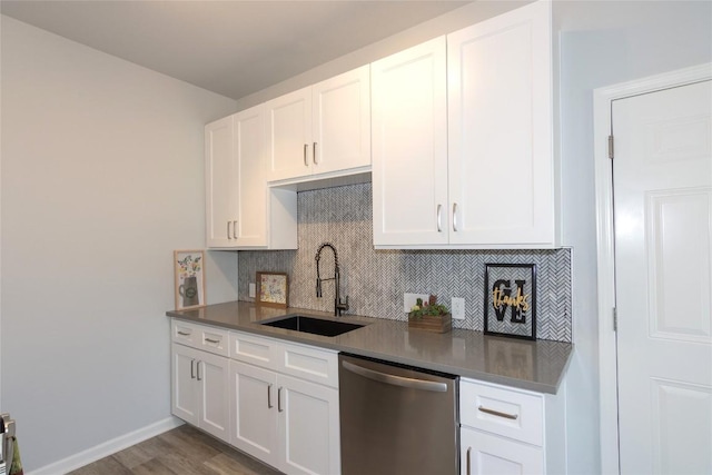 kitchen featuring tasteful backsplash, stainless steel dishwasher, white cabinets, a sink, and baseboards