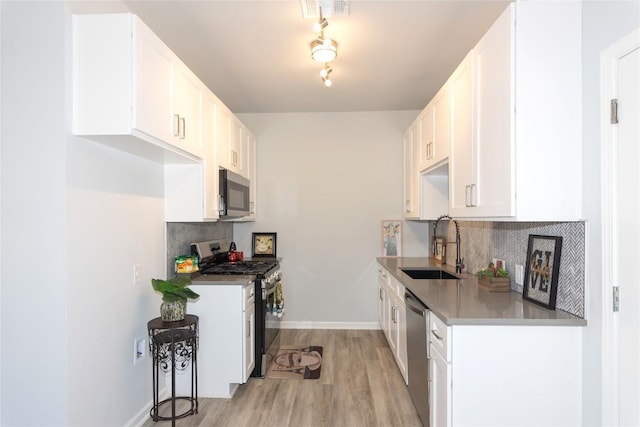 kitchen featuring light wood-type flooring, tasteful backsplash, appliances with stainless steel finishes, and a sink