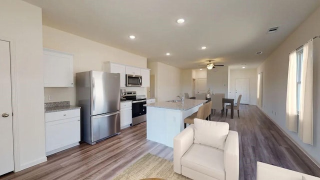 kitchen featuring a center island with sink, visible vents, appliances with stainless steel finishes, white cabinetry, and a sink