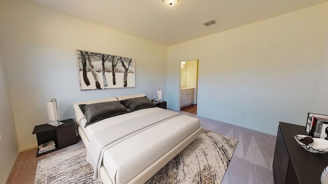 carpeted bedroom with visible vents, connected bathroom, and baseboards