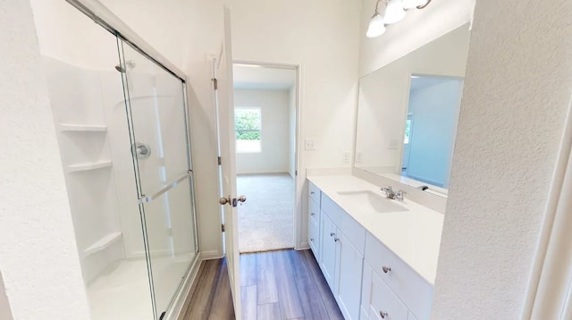 full bathroom with a stall shower, wood finished floors, and vanity