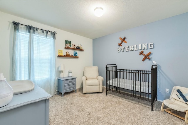 bedroom featuring a nursery area, a textured ceiling, carpet flooring, and baseboards